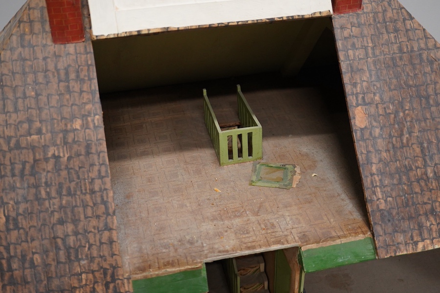 A 1920s/30s commercially produced dolls house, possibly by Tri-ang, of plywood construction, overlaid with printed paper roof tiles and brickwork, and tinplate windows and window frames, comprising of four rooms with bay